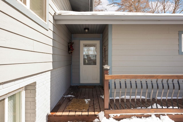 snow covered property entrance featuring brick siding