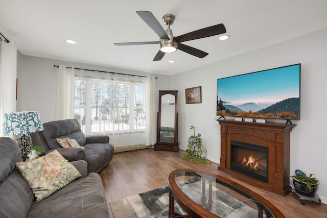 living area featuring wood finished floors, baseboards, a ceiling fan, recessed lighting, and a glass covered fireplace