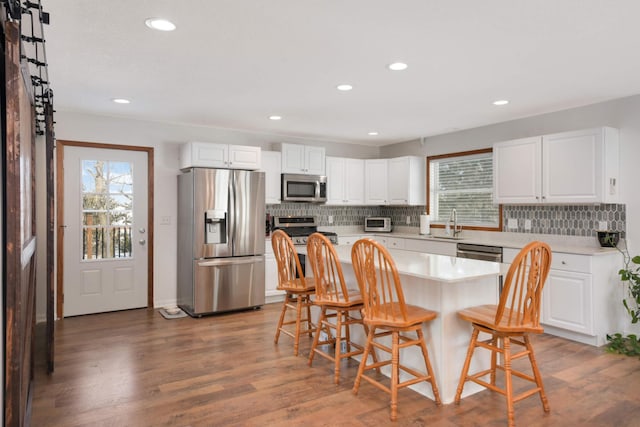 kitchen featuring a breakfast bar, a sink, stainless steel appliances, light countertops, and light wood-type flooring