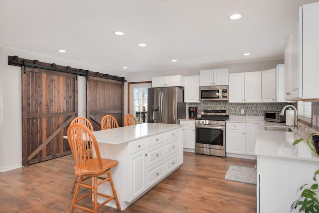 kitchen with a center island, a breakfast bar area, a barn door, stainless steel appliances, and a sink