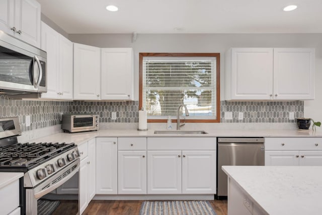 kitchen featuring a toaster, light countertops, stainless steel appliances, white cabinetry, and a sink