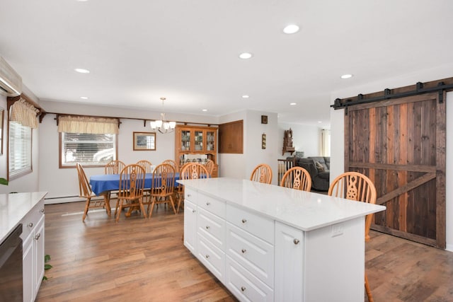 kitchen featuring white cabinetry, light wood-type flooring, a barn door, and black dishwasher