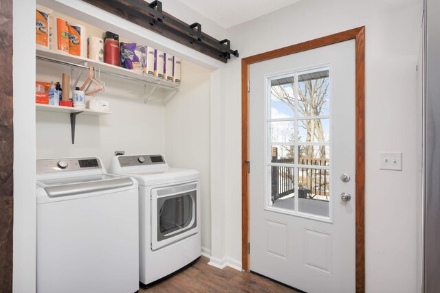 laundry room featuring dark wood-type flooring, a barn door, independent washer and dryer, and laundry area