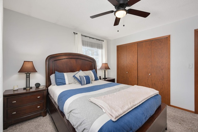 bedroom featuring a ceiling fan, light colored carpet, a closet, and baseboards