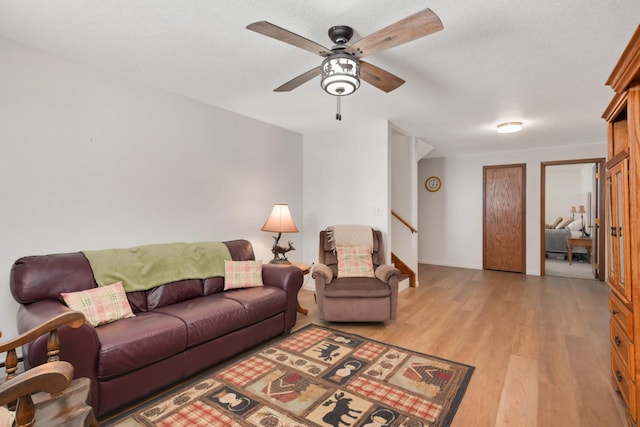 living room with light wood-style flooring, stairs, and ceiling fan