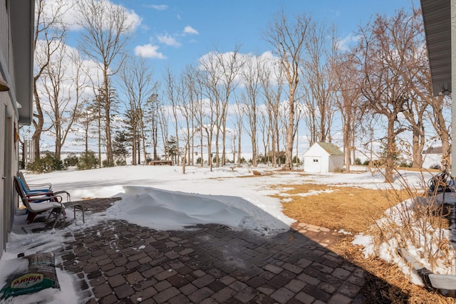 yard covered in snow featuring an outbuilding and a patio area