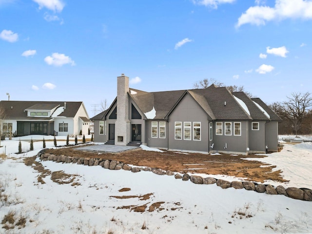 snow covered property with a chimney and a garage