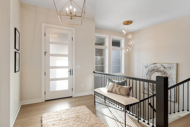 foyer entrance featuring baseboards, an inviting chandelier, and wood finished floors