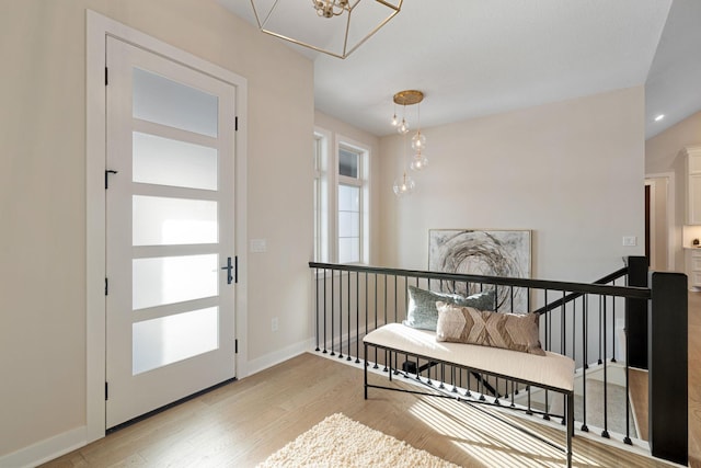 entrance foyer featuring light wood finished floors, a notable chandelier, and baseboards