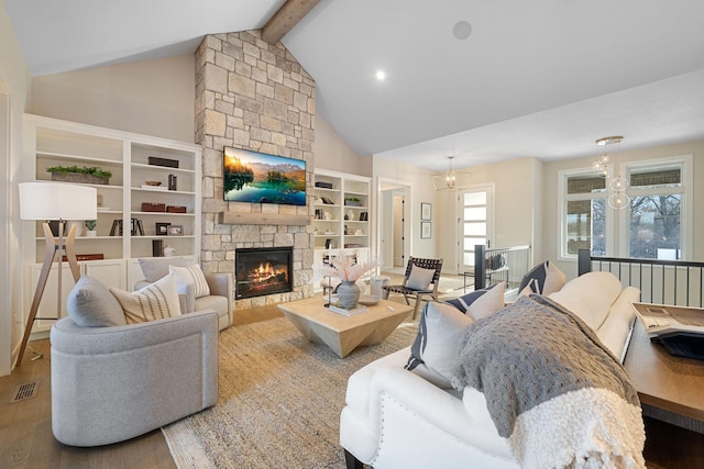 living area with wood finished floors, visible vents, high vaulted ceiling, a stone fireplace, and beamed ceiling