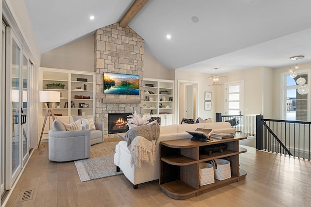 living area featuring visible vents, beam ceiling, a notable chandelier, wood finished floors, and a stone fireplace