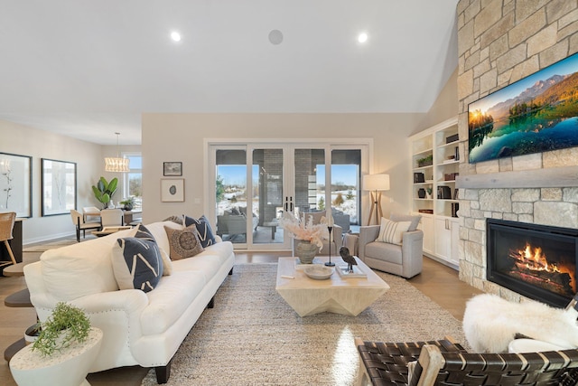 living area with a stone fireplace, lofted ceiling, recessed lighting, and wood finished floors