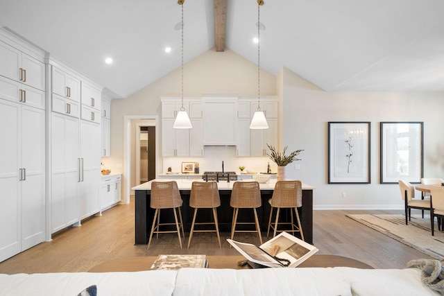 kitchen featuring light countertops, light wood-style flooring, a breakfast bar area, and beam ceiling