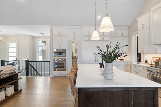 kitchen with light countertops, vaulted ceiling, a kitchen island, and stainless steel appliances