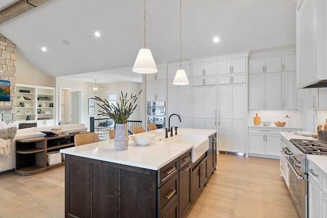 kitchen featuring light wood finished floors, a sink, white cabinets, light countertops, and dark brown cabinets