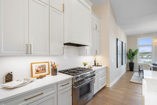 kitchen featuring baseboards, light countertops, light wood-style floors, stainless steel stove, and white cabinets