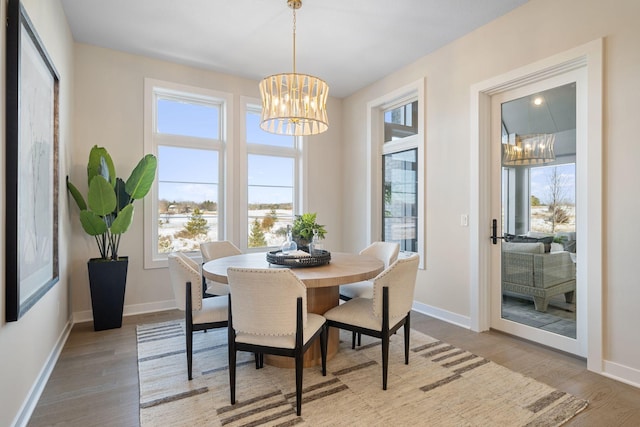 dining space with a wealth of natural light, a notable chandelier, and wood finished floors