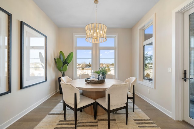 dining room with dark wood-style floors, an inviting chandelier, and baseboards