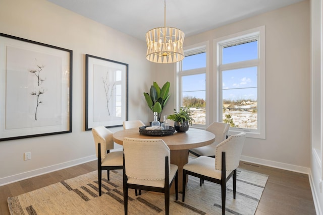 dining area featuring a notable chandelier, baseboards, and wood finished floors