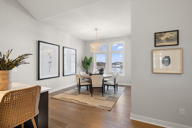 dining space featuring a notable chandelier, baseboards, and dark wood-style flooring