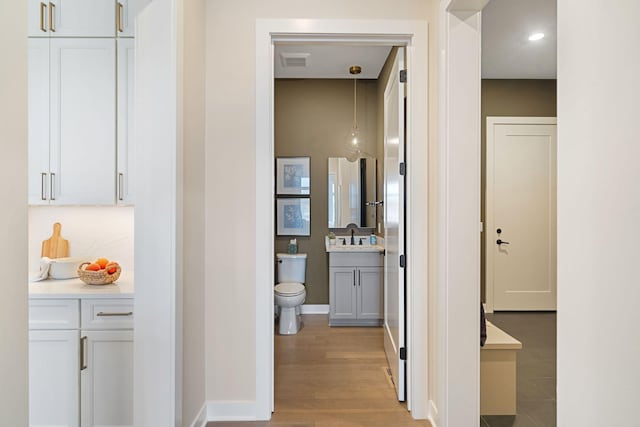 hallway with visible vents, light wood-type flooring, and baseboards