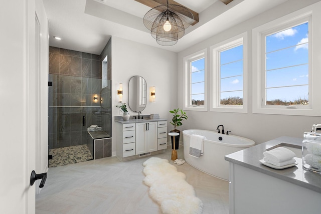 bathroom with a tray ceiling, a soaking tub, a stall shower, and vanity