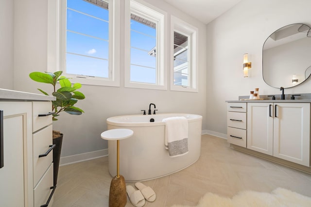 bathroom with vanity, a soaking tub, baseboards, and tile patterned flooring