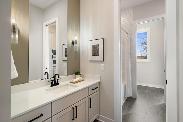 bathroom with vanity, shower / bath combo with shower curtain, and baseboards