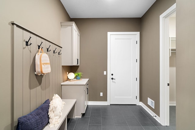 mudroom featuring dark tile patterned floors, visible vents, and baseboards