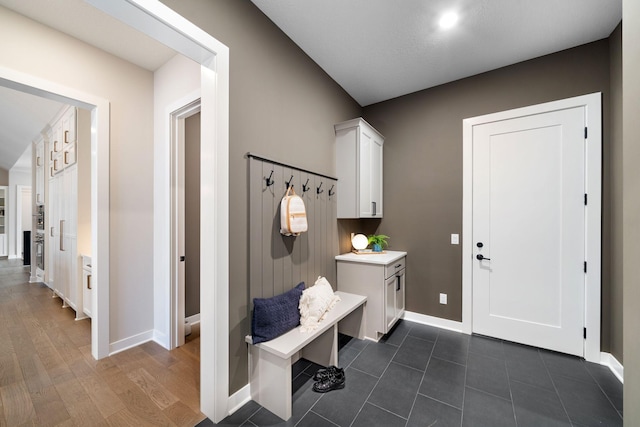 mudroom with dark wood finished floors and baseboards