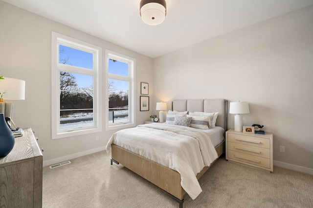 bedroom with visible vents, baseboards, and light carpet