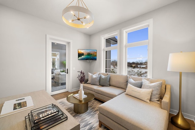 living area with a chandelier, baseboards, and wood finished floors