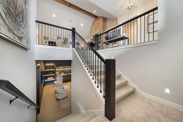 stairs with baseboards, high vaulted ceiling, beam ceiling, carpet flooring, and a chandelier