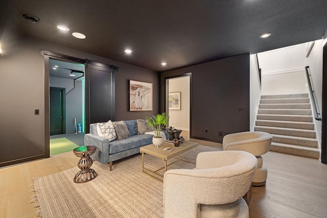 living room with stairway, wood finished floors, baseboards, recessed lighting, and a barn door