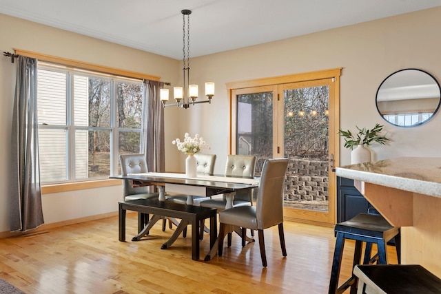 dining room featuring light wood finished floors, a notable chandelier, a healthy amount of sunlight, and baseboards