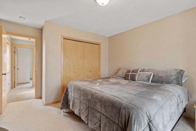 bedroom with baseboards, light carpet, and a closet