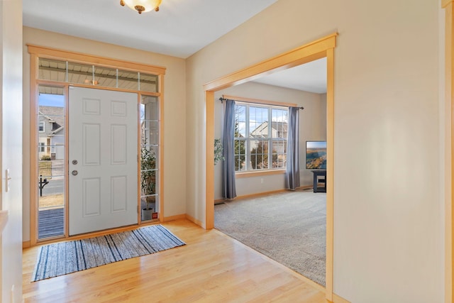 carpeted foyer with baseboards and wood finished floors