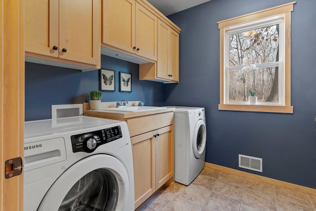 laundry room with visible vents, baseboards, washer and dryer, cabinet space, and a sink