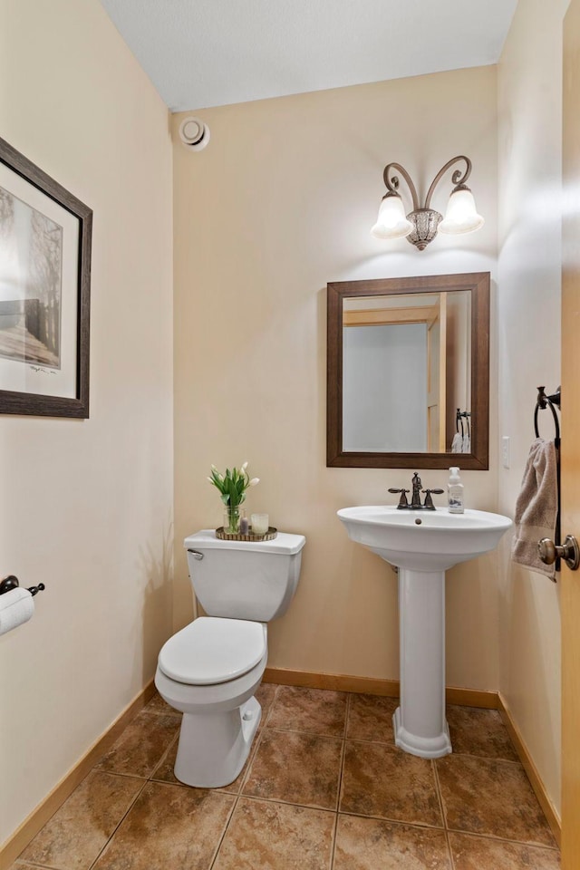 half bath with tile patterned flooring, toilet, and baseboards