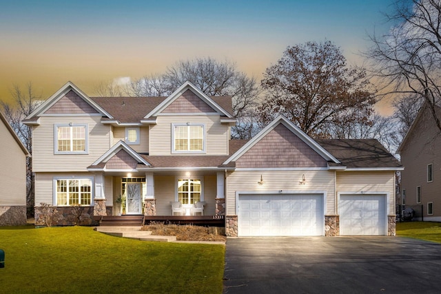 craftsman house with roof with shingles, a yard, a garage, stone siding, and driveway