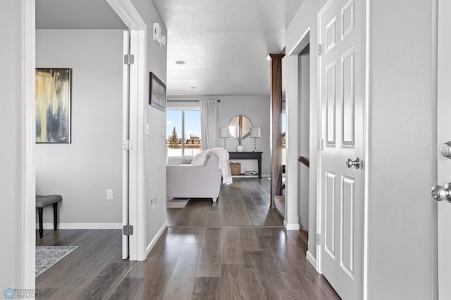 hallway featuring dark wood finished floors, a textured ceiling, and baseboards