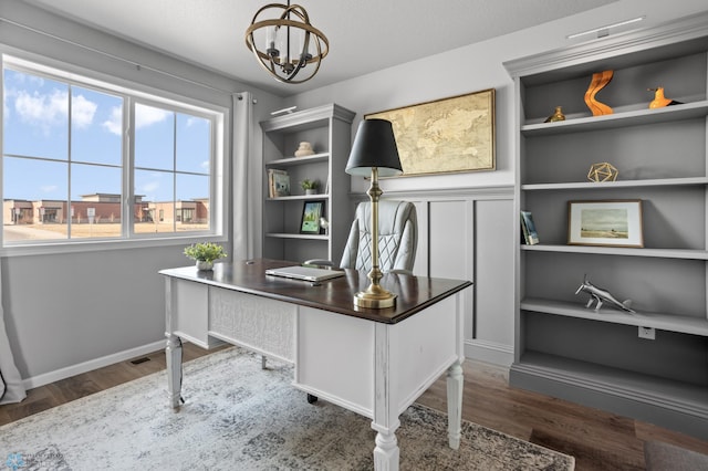 office with baseboards, dark wood-type flooring, an inviting chandelier, and built in shelves