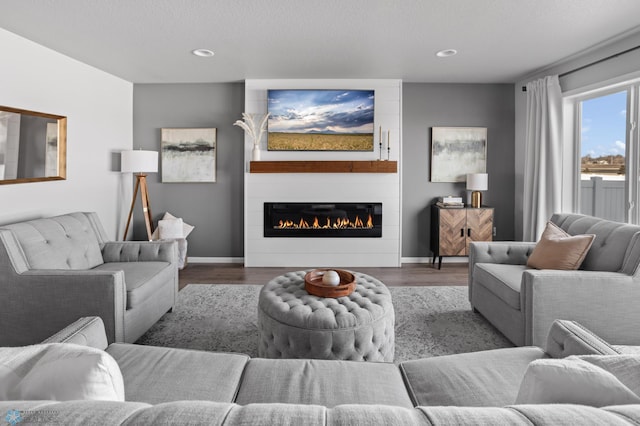 living area featuring recessed lighting, a fireplace, baseboards, and wood finished floors