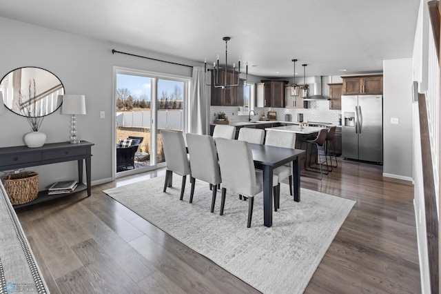 dining area with baseboards, a notable chandelier, and wood finished floors