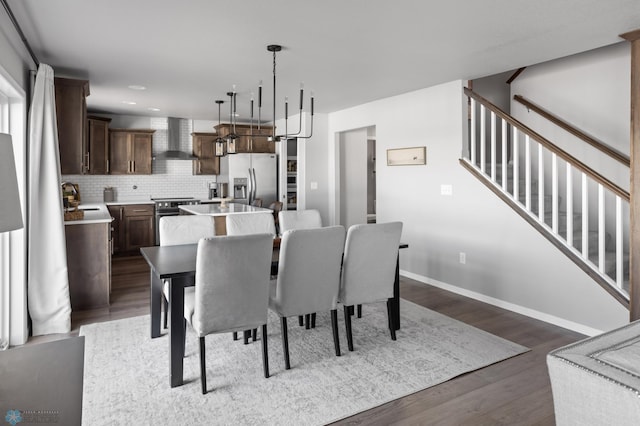 dining space featuring dark wood-type flooring, baseboards, stairs, recessed lighting, and a notable chandelier