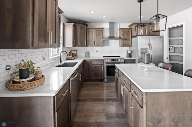 kitchen featuring a kitchen island, decorative backsplash, stainless steel appliances, wall chimney exhaust hood, and a sink