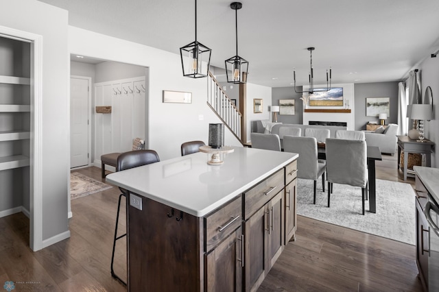 kitchen with dark brown cabinets, a kitchen island, a kitchen bar, and dark wood-style flooring