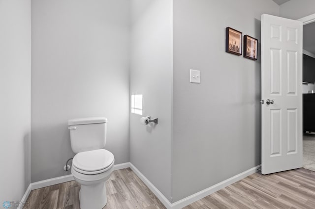 bathroom with baseboards, toilet, and wood finished floors