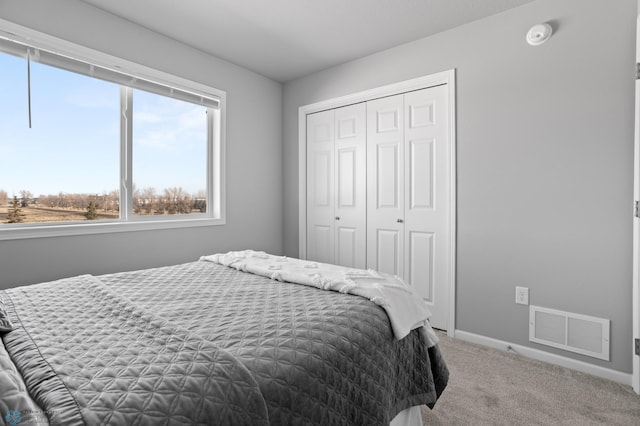 bedroom with carpet, visible vents, a closet, and baseboards