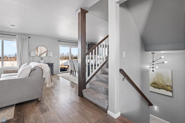 interior space with wood finished floors, baseboards, ornate columns, stairs, and a textured ceiling